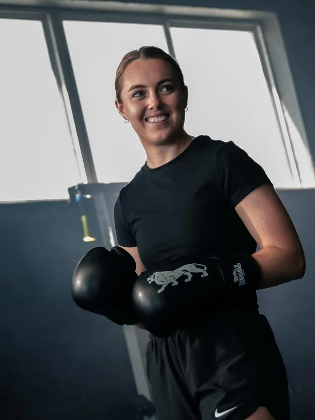 A boxer smiling in a Cape Town studio, gloves up