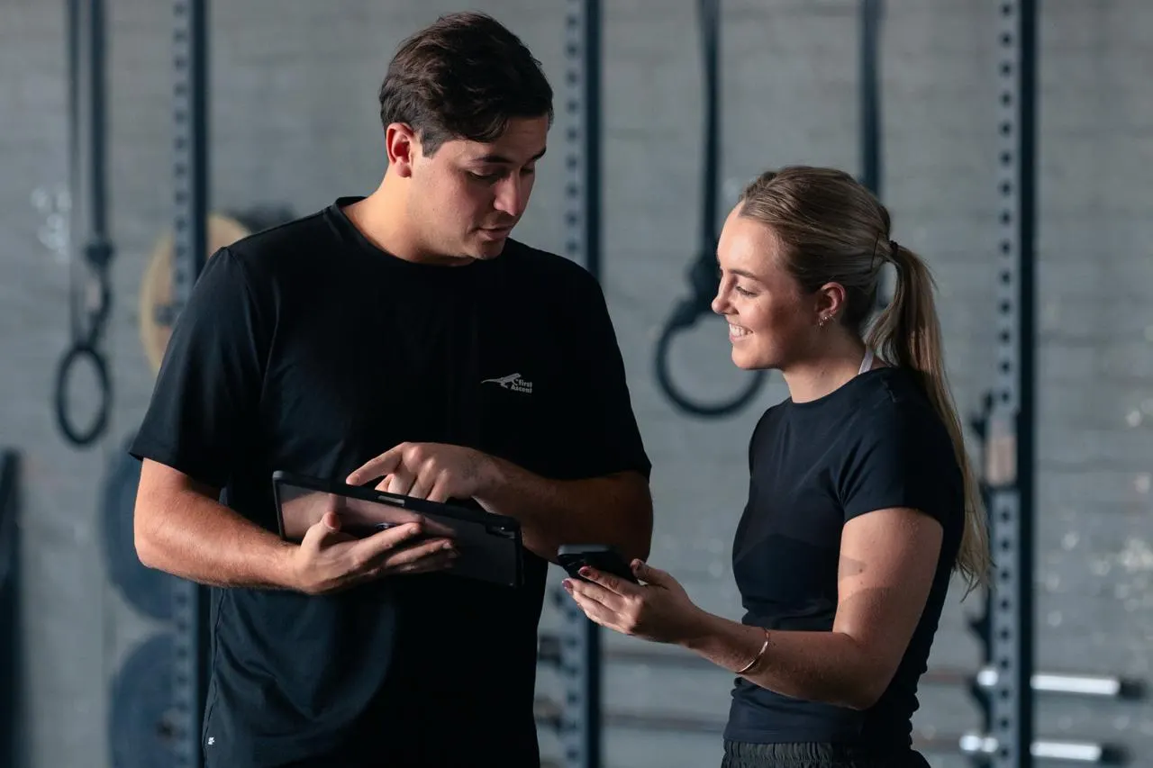 A studio coach and a member looking at a booking together on a phone and tablet
